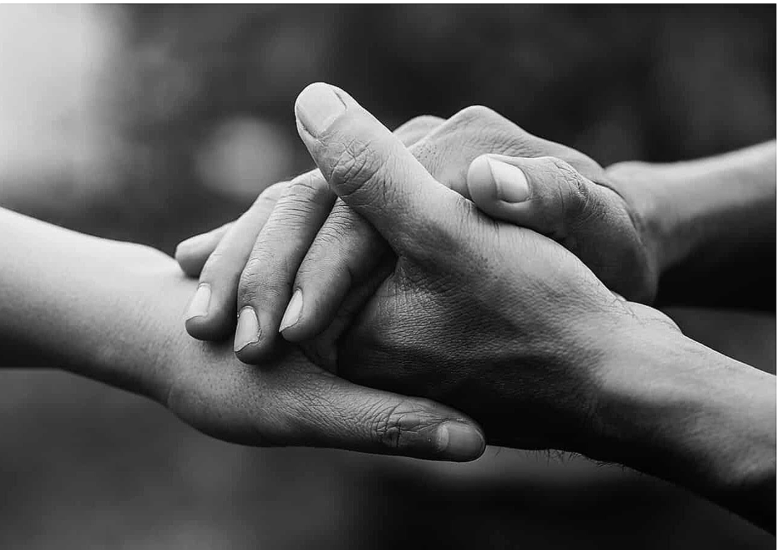 Two people holding hands, offering comfort